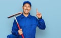 Bald man with beard wearing glass cleaner uniform and squeegee surprised with an idea or question pointing finger with happy face, Royalty Free Stock Photo