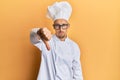 Bald man with beard wearing professional cook uniform looking unhappy and angry showing rejection and negative with thumbs down