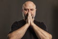 The bald man folded his hands in prayer by his face. Faith and hope. Dark background Royalty Free Stock Photo