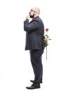 A bald man in glasses with a beard holds a red rose behind his back and looks up. Dressed in a formal suit. Full growth. Isolated Royalty Free Stock Photo