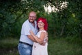 Bald man in glasses embrace with tenderness woman with pink hair in green forest. Diversity Couple Royalty Free Stock Photo