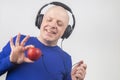 Bald man with headphones listens to music through a red apple player. Metaphor and concept of vitamin benefits in music and sound Royalty Free Stock Photo