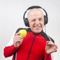 Bald man with headphones listens to music through a yellow apple player. Metaphor and concept of vitamin benefits in music and Royalty Free Stock Photo