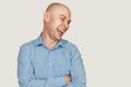 Bald man laughing mockingly at something or someone on a gray background Royalty Free Stock Photo