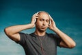 A bald man listens and enjoys music in large headphones with his eyes closed on a greenish background Royalty Free Stock Photo
