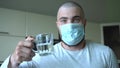 A Bald Man In A Protective Mask Can`t Drink Water From A Glass. The absurdity of the situation. Epidemic, Pandemic, Self