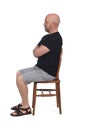 Bald man with sandals t-shirt and shorts sitting on white background, look side and arms crossed Royalty Free Stock Photo