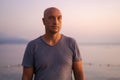 Bald man standing on beach and looking at amazing sunset and sea with calm Royalty Free Stock Photo