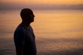 Bald man standing on beach and looking at amazing sunset and sea with calm Royalty Free Stock Photo