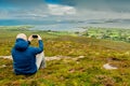 Bald man taking picture on his smart phone of scenic view on Clew Bay from Croagh Patrick, Royalty Free Stock Photo