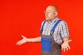 Bald man in work clothes and safety glasses spreads his hands Royalty Free Stock Photo