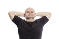 Bald middle-aged man in a black T-shirt, hands behind his head, smiling. Isolated over white background Royalty Free Stock Photo