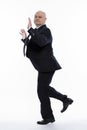 A bald middle-aged man in a strict black suit jumps funny. Business success. Full height. White background. Vertical Royalty Free Stock Photo