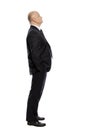 Bald middle-aged man in a suit looks up, full-length, side view. Isolated on white background Royalty Free Stock Photo