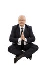 Bald middle-aged man in a suit sits in a yoga pose, hands in prayer, is isolated on a white background