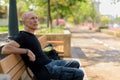 Bald senior tourist man thinking while sitting on the wooden ben Royalty Free Stock Photo