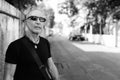 Bald senior tourist man thinking while wearing sunglasses against old cement wall in the streets outdoors Royalty Free Stock Photo