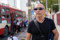 Bald senior tourist man thinking while wearing sunglasses at the