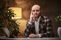 Bald european well-dressed thinking businessman sitting in the office at a table with notebook, wearing stylish jacket Royalty Free Stock Photo