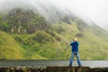 Bald tourist taking picture on his smart phone of a beautiful scenery.