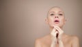 Bald woman folding her hands in prayer. beige background