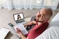 A bald young happy man is working at a laptop and writing something down on paper. Top view. The concept of online courses and Royalty Free Stock Photo