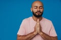 Bald young man with beard posing while making pray gesture