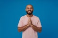 Bald young man with beard smiling while making pray gesture