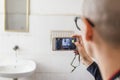 Bald Hispanic young woman taking photos with her cellphone in the washroom Royalty Free Stock Photo