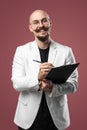 Balded man with mustache and beard in a business suit holding clipboard and pen isolated background.Concept of teacher