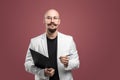 Balded man with mustache and beard in a business suit holding clipboard and pen isolated background.Concept of teacher