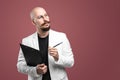 Balded man with mustache and beard in a business suit holding clipboard and pen isolated background.Concept of teacher