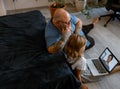 Baldhead man with cute little child talk to woman at videochat via laptop sitting on floor