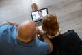 Baldhead father with girl talk to lady at videocall via modern laptop sitting on floor at home