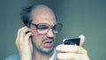 Balding man with glasses hardly uses a smartphone. Humor