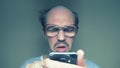 Balding man with glasses hardly uses a smartphone. Humor