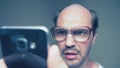Balding man with glasses hardly uses a smartphone. Humor