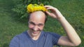 Balding man with a wreath of dandelions on his head. looking at the camera Royalty Free Stock Photo