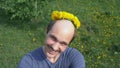 Balding man with a wreath of dandelions on his head. looking at the camera Royalty Free Stock Photo