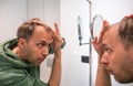 Balding middle age man looks in mirror and checks how much hair he lost Royalty Free Stock Photo