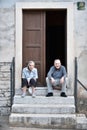 Bale / Croatia - 7/18/2019: Older man and woman sitting on the steps in front of their doorstep