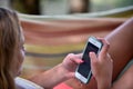 Bale / Croatia - 7/18/2019: Teenage girl lying in a hammock, looking at their mobile phones, having fun.