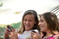 Bale / Croatia - 7/18/2019: Two teenage girls lying in a hammock, looking at their phones