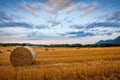 Bale of hay on wheat field against dramatic morning sky