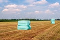 Bales of compressed hay packed with foil and stacked on mown grassland Royalty Free Stock Photo