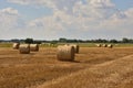 Bales of straw after harvest in stubble under a blue sky and white clouds Royalty Free Stock Photo