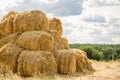Bales of yellow golden straw stacked in a pile at the farm with blue sky on the background . Food for Farm animals. Royalty Free Stock Photo