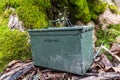 Balgale, Latvia - January 29, 2022: Green geocaching ammo box next to a mossy tree Royalty Free Stock Photo