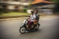 Panned movement image of two balinese men in traditional dress driving a bike in Ubud. Bali. Indonesia Royalty Free Stock Photo