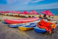 BALI, INDONESIA - MARCH 11, 2017: Beautiful sunny day with a row of red unmbrellas and some boats on the yellow sand, in